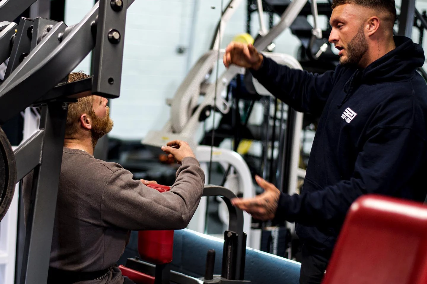 A coach supporting a member on the gym floor at S20 Health and Fitness
